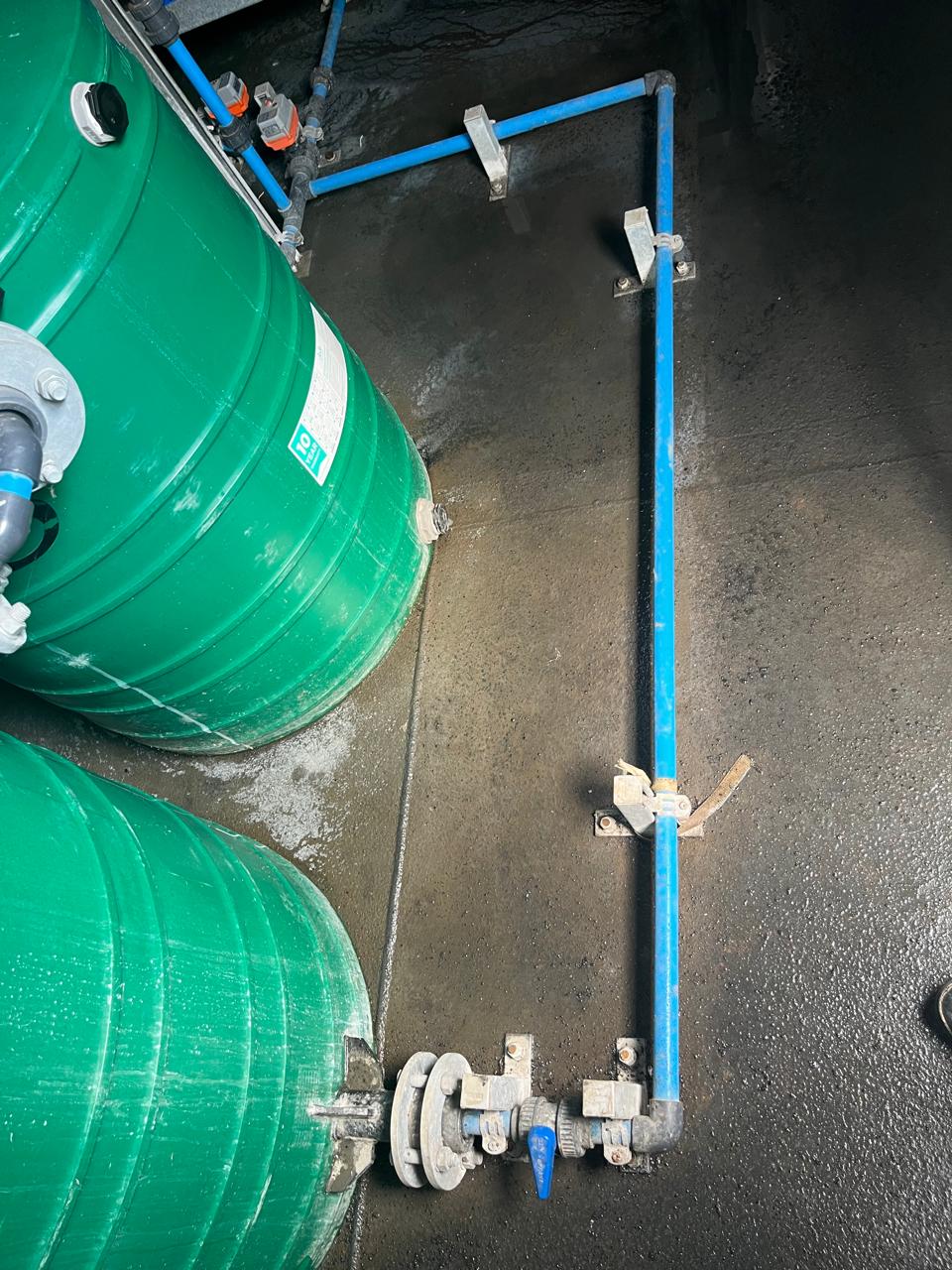 Green fibreglass conservancy and treatment tanks with valved manifold