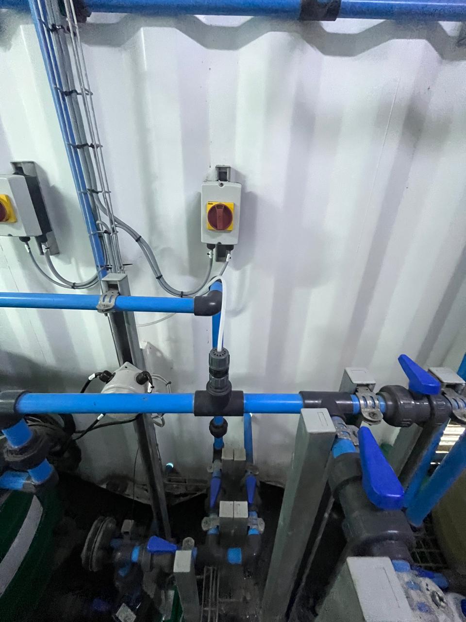 A greywater treatment skid with blue piping, valves and an isolator switch