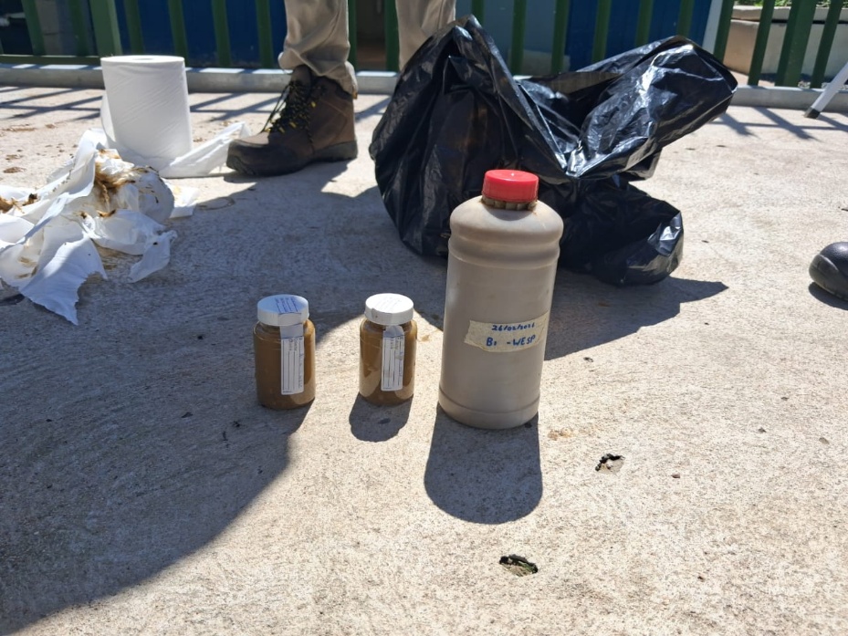 Labelled sample jars and a sample bottle on site concrete during a field visit